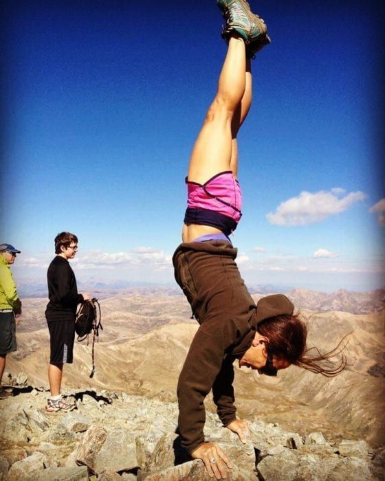 Climber doing handstand at summit
