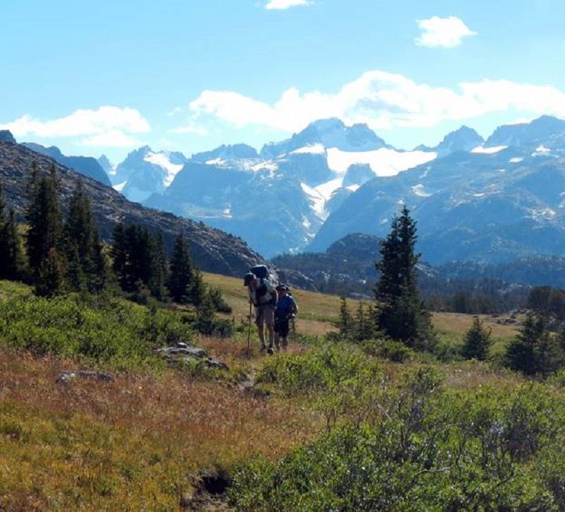 Two people hiking with mountains in the background 