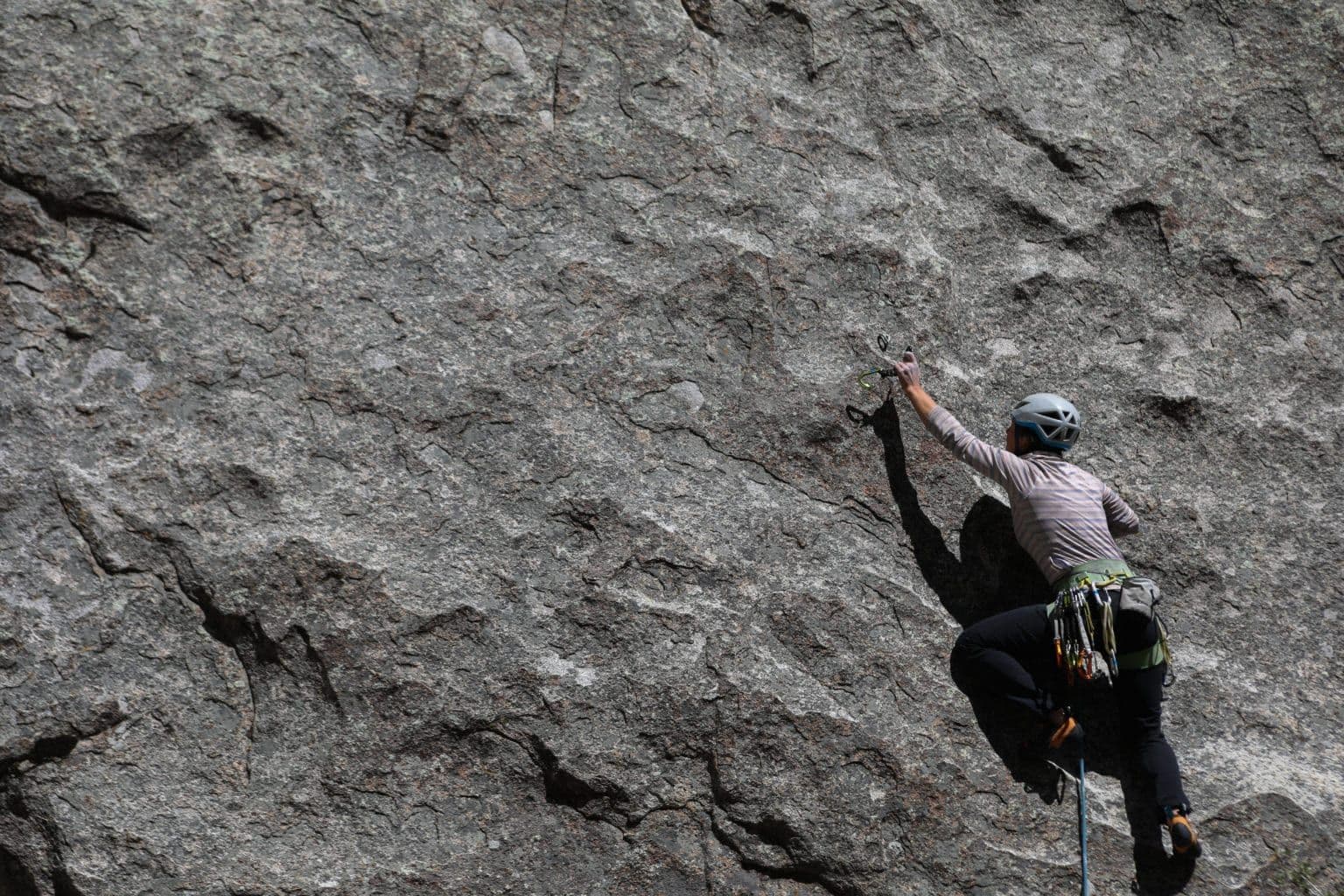Person climbing steep mountain in city of rocks 
