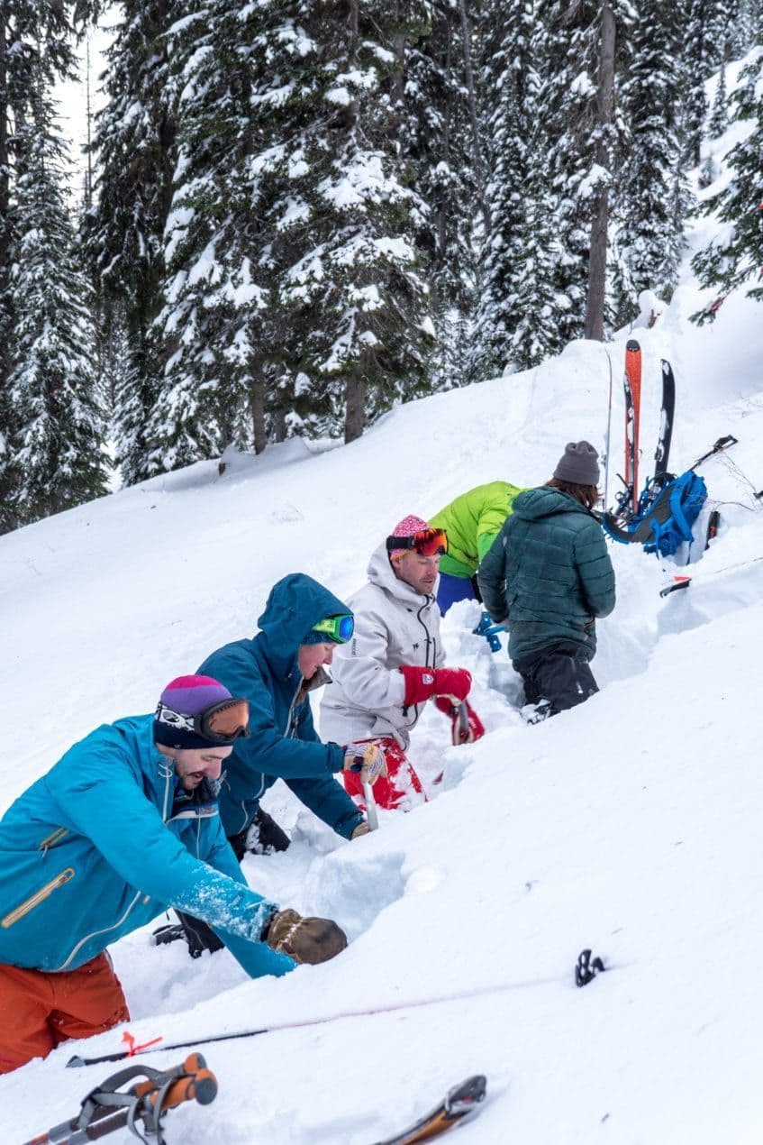 Group of skiers shoveling snow 
