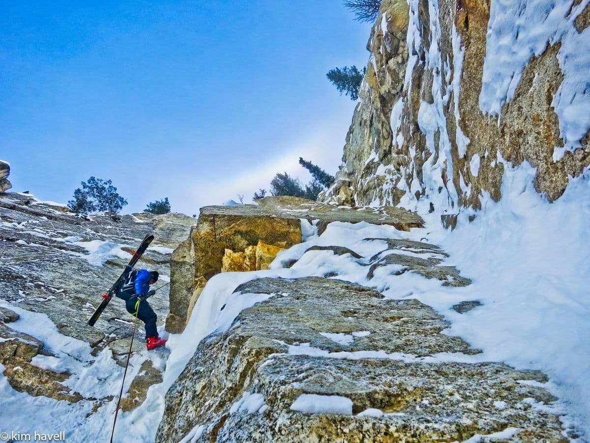 Skier climbing rocky and snowy terrain