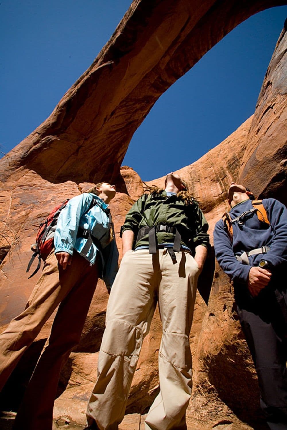 Three hikers admiring arch of a canyon