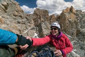 A female rock climber reaches the top of a pitch on the Grand Teton.