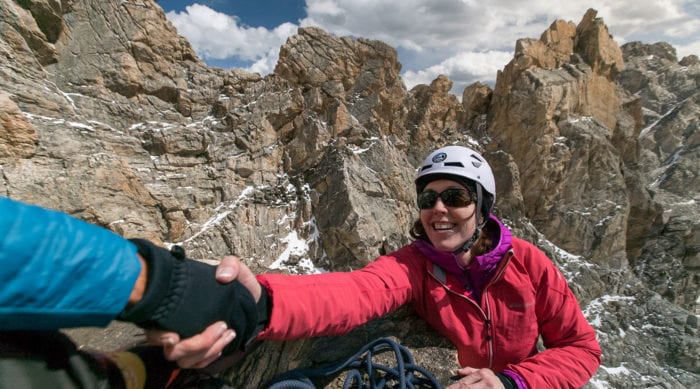 A female rock climber reaches the top of a pitch on the Grand Teton.