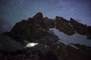 Camp tent illuminated under the starry night sky on the Grand Teton.