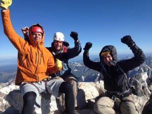Three male rock climbers celebrate on the summit of the Grand Teton.