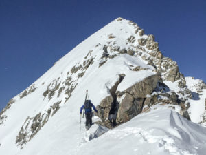 a skier climbing up the ridge of a mountain