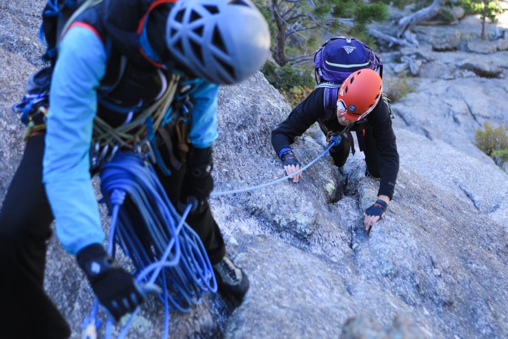 a guide helps a climber up a rock wall