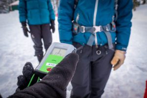 a skier running an avalanche safety beacon function check