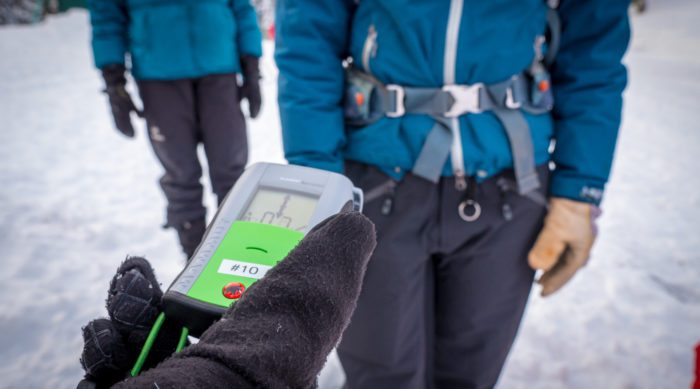 a skier running an avalanche safety beacon function check