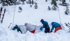 group of skiers digging a pit in the snow