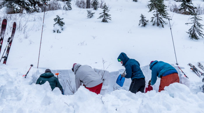 group of skiers digging a pit in the snow
