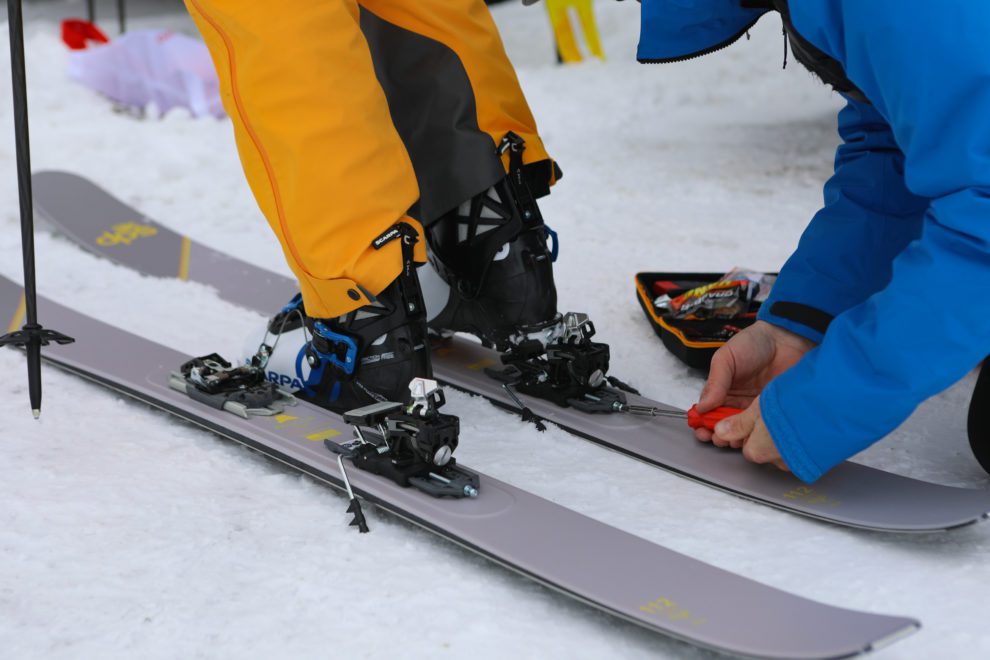 a guide adjusting a skiers bindings