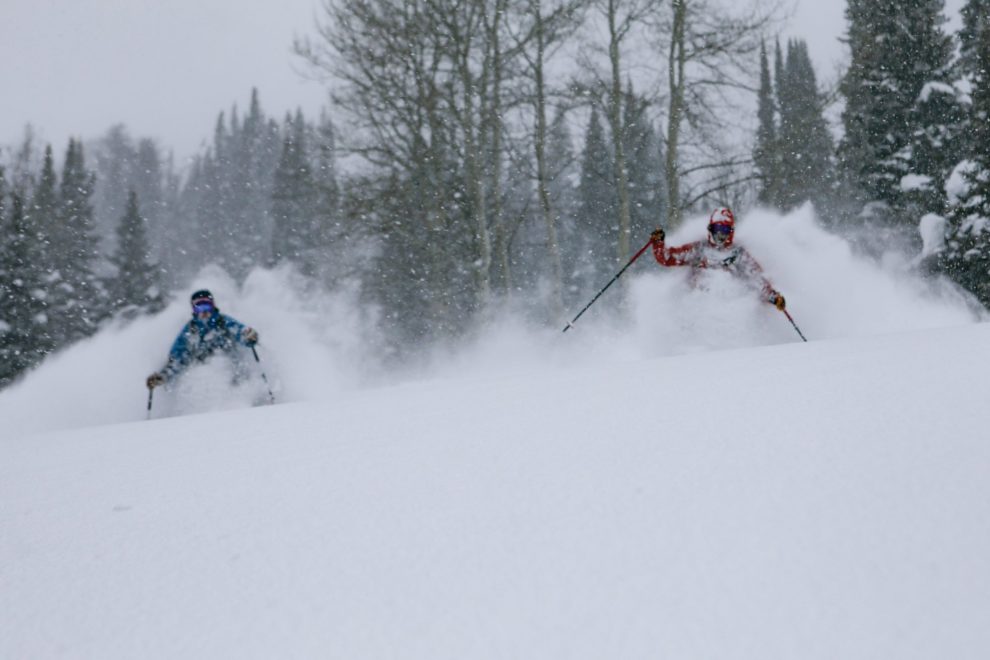 Two skiers in powder on a stormy day.