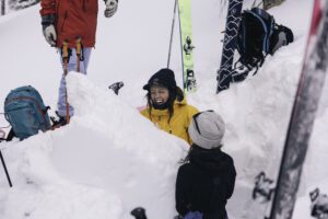 Female smiles while digging a snow pit in an avalanche course.