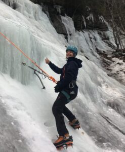 A happy client gives a "thumbs up" while ice climbing.