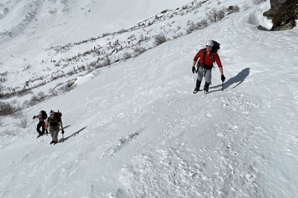 3 mountaineers ascent a snow-covered slope on a Spring day.