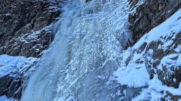 a climber near the summit of a frozen waterfall