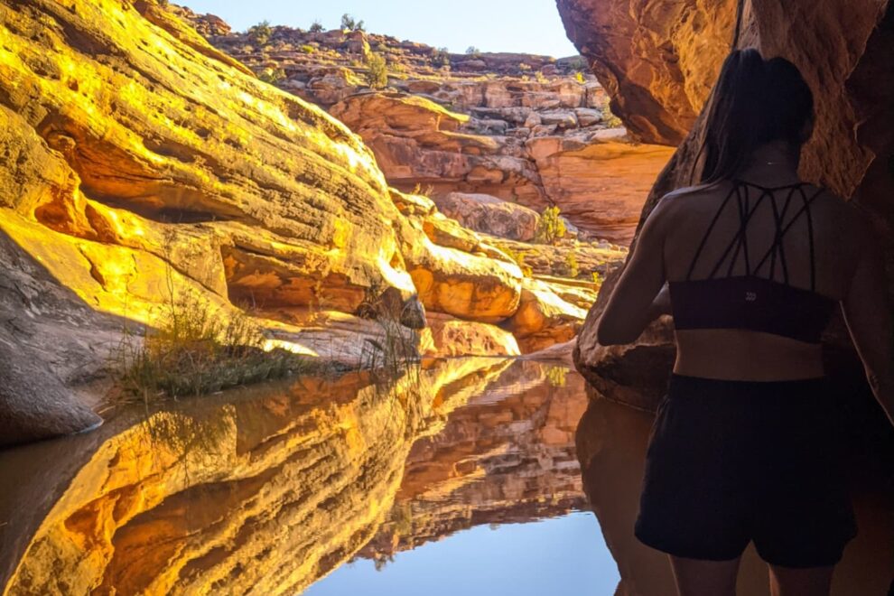 A woman stands in the shade in a canyon in Moab, Utah.
