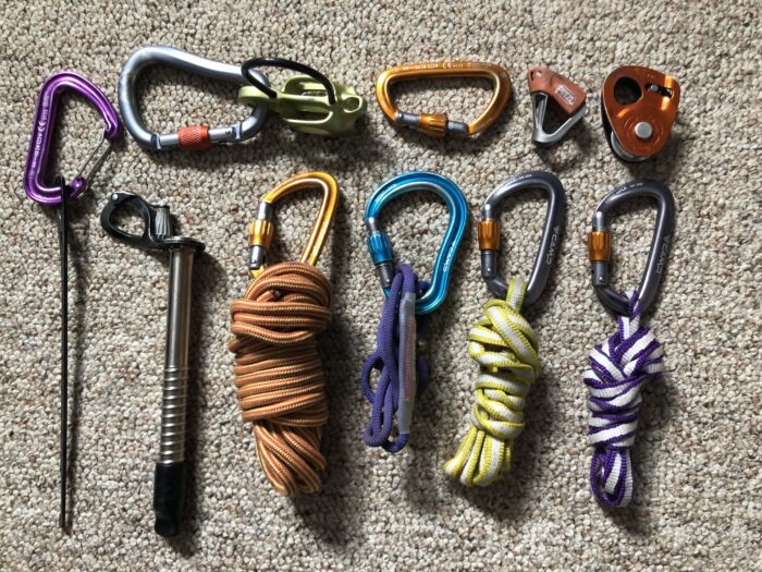 An assortment of ski mountaineering belay devices, ice screws, slings, cordelettes, and other tools